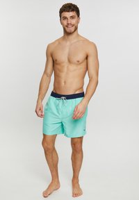 Shorts de bain bleu clair avec un gros-grain marine, fermeture à cordons et un petit logo brodé sur la jambe gauche. Texture lisse, longueur jusqu'aux genoux.