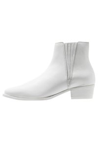 Botas de tobillo de cuero blanco con punta afilada y tacón bajo tipo bloque. Presenta costuras verticales en la parte trasera. Textura lisa en toda su superficie.