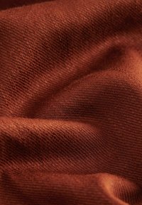 Tissu texturé d'un riche couleur orange brûlé, présentant un tissage doux avec des fibres visibles, créant une apparence douce et fluide.