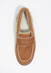 Zapatilla de ante marrón con un suave forro de piel de oveja, puntera redonda, correa con corte, y detalles de costura blanca, suela de goma plana.