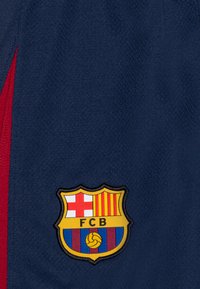 Marinsportshorts med röda accenter, utrustade med en broderad FC Barcelona-emblem. Materialet har en strukturerad yta.