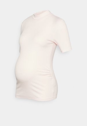 Top de maternidade rosa claro feito de tecido canelado, com um decote alto e mangas curtas, apresentando detalhes franzidos nas laterais.