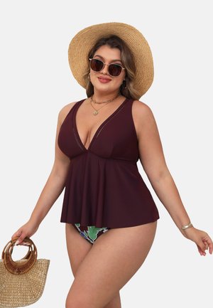 Bordeaux tankini-top met een v-hals, decoratieve stiksels en een uitlopend zoom; gecombineerd met bloemige bikini-broekjes en een strohoed.