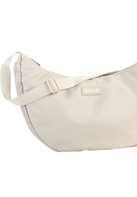 Hellbeige Umhängetasche aus glattem Stoff, ausgestattet mit einem breiten Schultergurt und einem kleinen vorderen Etikett mit dem Text "Bench.".