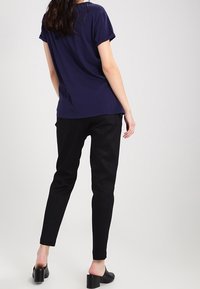 Námořnická modrá blůza s krátkým rukávem, volný střih, doplněná o úzké černé kalhoty. Hladká látka. Černé boty na blokovém podpatku zvýrazňují vzhled.