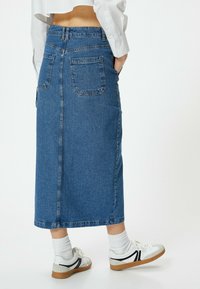 Denimhame keskipitkä, keskitumman sininen, kahdella takataskulla ja keskisaumalla. Parin valkoisten lenkkareiden ja nilkkasukkien kanssa.