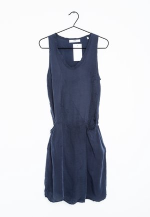 Robe sans manches bleu foncé avec un col rond, suspendue à un cintre en fil noir sur un fond blanc.