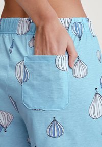 Lichtblauwe katoenen shorts met een zak, versierd met een patroon van luchtballonnen in blauw en wit. Zachte textuur, elastische tailleband.