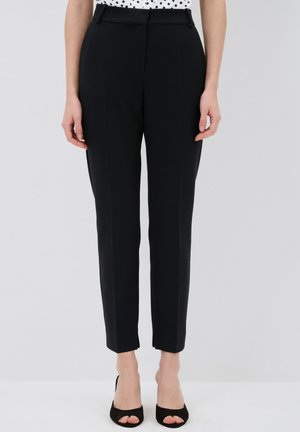 Tailored black trousers with a smooth fabric, slim fit, and ankle-length hem. Features a flat front and side pockets.