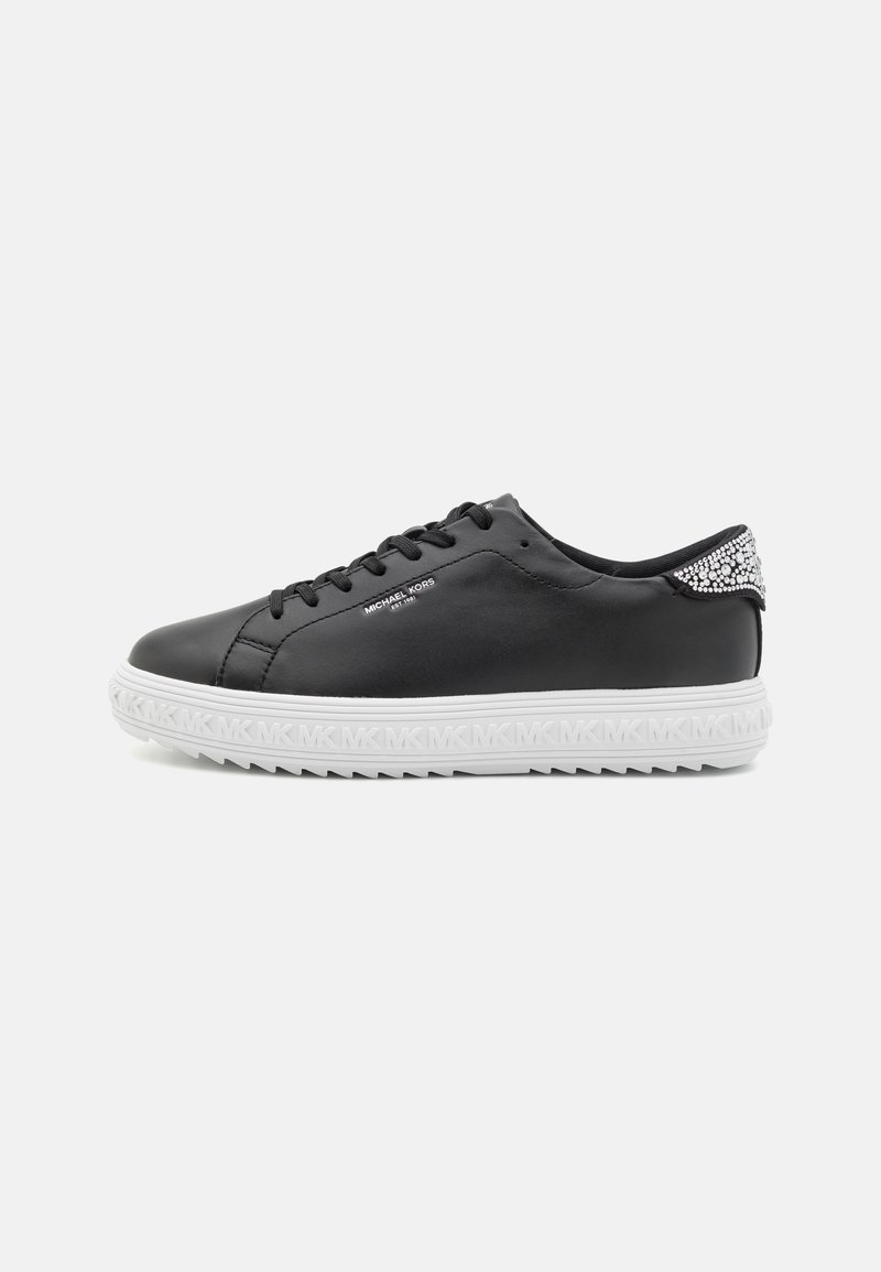 Baskets basses noires avec semelle blanche embossée MK, détail du talon serti de cristaux, lacets noirs, marquées "Michael Kors" sur le côté.