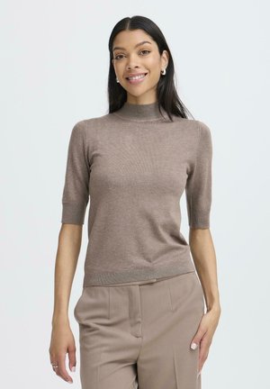 Brauner Kurzarmpullover mit hohem Kragen, schmaler Passform und gerippten Akzenten. Weicher Stoff und schlichtes Design, kombiniert mit beigen Hosen.