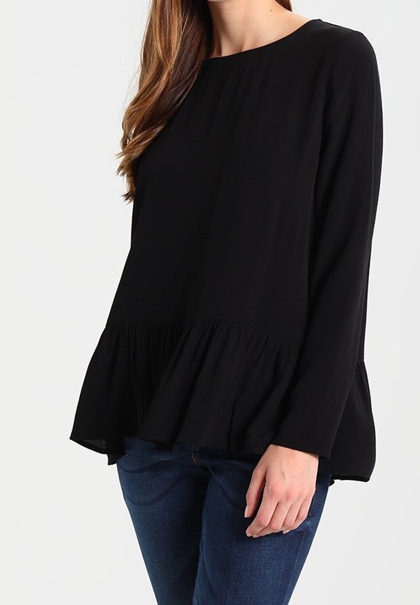 Blusa nera a maniche lunghe con scollatura tonda e orlo a peplo svasato. Tessuto morbido con vestibilità comoda, abbinata a jeans blu.