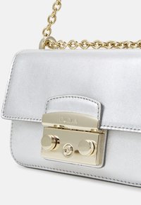 Srebro skórzana torebka na ramię z złotym łańcuszkiem i charakterystycznym zapięciem z dwoma okrągłymi akcentami oraz wygrawerowanym logo.