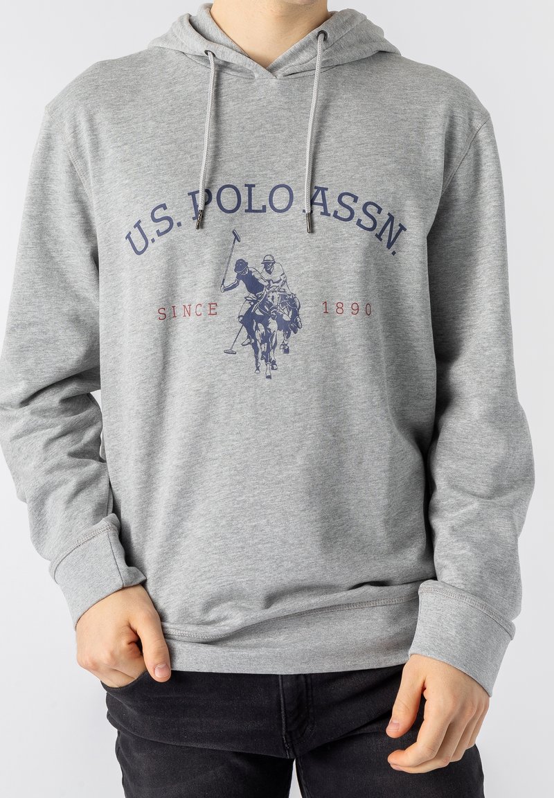 Sweat à capuche gris avec un motif frontal comprenant le texte "U.S. Polo Assn.", une illustration d'un joueur de polo, et la mention "Since 1890" en rouge, avec un cordon de serrage à la capuche.