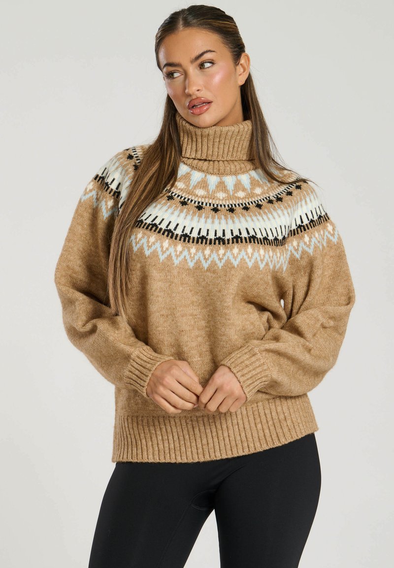 Turtlenecktröja i ljust brunt mao med ribbstickade ärmar och nederkant. Har ett geometriskt mönster i svart och ljusblått vid kragen.