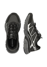 Svarta sportskor med en ventilerande meshuppdel, strukturerat mönster, reflekterande silverdetaljer och en flexibel gummisula med snörning.