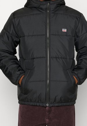 Svart vadderad jacka med huva, dragkedja framtill, justerbara manschetter och elastisk midja. Har en liten märkeslapp på bröstet.