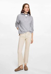 Gray knitted sweater with a zip collar, paired with light beige flared pants and brown slip-on shoes. Smooth texture and casual design.