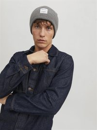 Donkerdenim jasje met borstzakken en knoopsluitingen, gecombineerd met een lichtgrijze geribde beanie met een logo-opdruk.