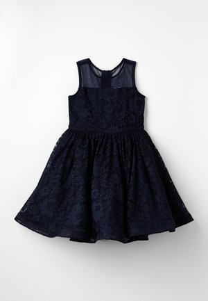 Robe bleu marine sans manches avec superposition en dentelle florale et empiècement transparent, jupe évasée, et fermeture éclair au dos, étalée à plat sur fond blanc.