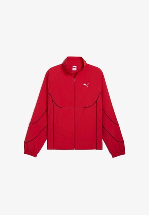 Jachetă ușoară roșie cu linii negre de accent, guler înalt, fermoar complet pe față și logo Puma pe piept. Dispune de mâneci lungi și manșete elastice.
