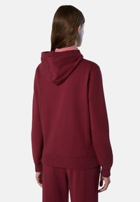 La sudadera con capucha burdeos cuenta con un corte relajado, puños y dobladillo acanalados, y está hecha de una tela suave con una textura lisa.