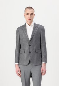 Blazer grigio a righe sottili realizzato in tessuto testurizzato, con due bottoni, revers a punta e due tasche frontali, abbinato a pantaloni grigi chiari.