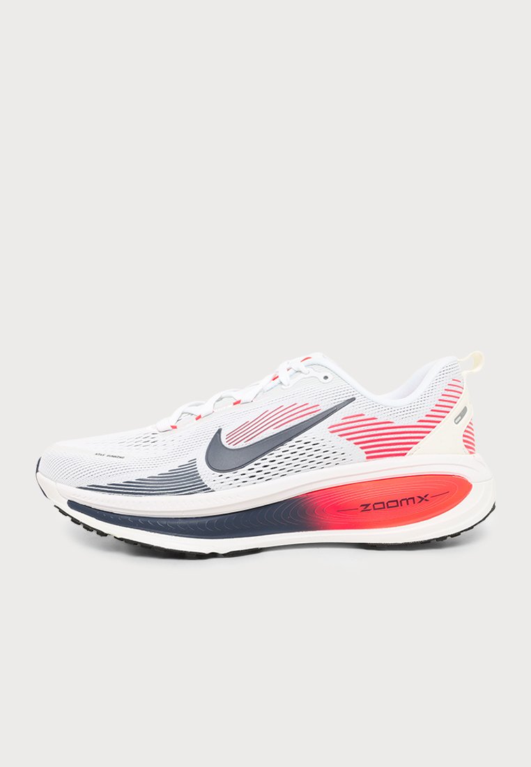 Zapatilla de running Nike blanca con el logotipo Swoosh gris, detalles rojos y una suela gruesa ZoomX, mostrada de perfil sobre un fondo liso.
