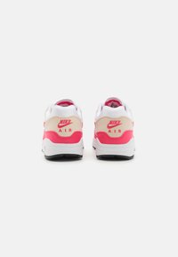 Sapatilhas Nike Air com um design de múltiplos materiais. Apresentam cores branca, bege e rosa vibrante; destaque do logo no calcanhar; colarinho almofadado.