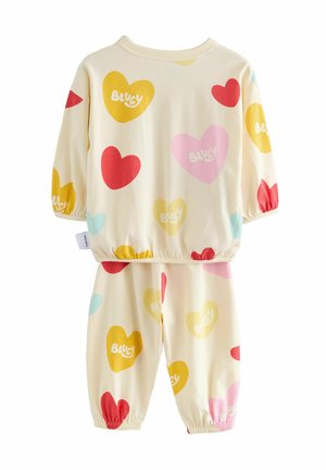 Cotton loungewear set featuring long sleeves and elastic cuffs, in cream with colorful heart patterns in red, pink, yellow, and blue.