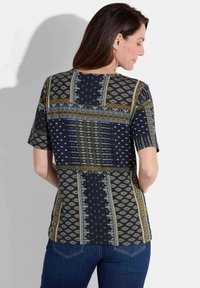 Marineblauw T-shirt met korte mouwen en ingewikkelde geometrische patronen in goud, teal en wit. Ontworpen met een relaxte pasvorm en zachte stof.