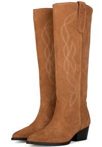 Botas de ante marrón hasta la rodilla con puntera afilada, que presentan un ribete decorativo en un patrón en espiral y un tacón bajo.