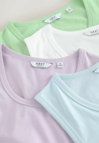 Quatre t-shirts à col rond pliés en vert pastel, blanc, lilas et bleu clair avec les étiquettes "NEXT Regular Fit" visibles.