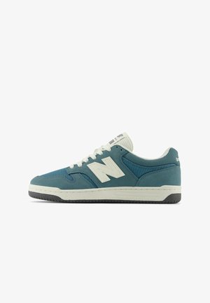 Baskets New Balance basses bleu sarcelle et blanches avec des panneaux en mesh et en suède, des lacets blancs et une semelle noire et blanche.