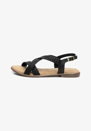 Sandalias de tiras tejidas negras con suela plana, que cuentan con un upper texturizado y detalle de hebilla. La plantilla es de color marrón claro, con un acabado suave.