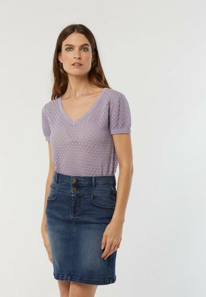Haut tricoté lilas clair avec un décolleté en V et des manches courtes, associé à une jupe crayon en denim foncé avec deux boutons à l'avant et des poches.