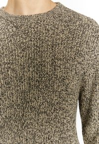 Maglione a maglia beige e nero con un motivo testurizzato, caratterizzato da un colletto rotondo e di spessore medio, adatto per essere indossato a strati.
