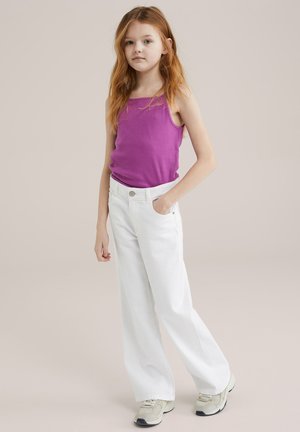 Lilla top med tykke stropper, hvide vidde jeans med forlommer og knaplukning, og lyse sneakers.