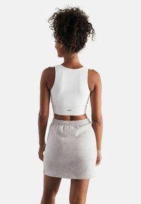 Top corto bianco a coste con scollatura rotonda abbinato a una mini gonna grigia chiara con elastico in vita.