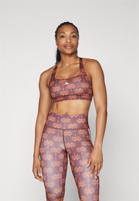 Sportsbh og høyt liv leggings i brunt med oransje palmemønster; laget av glatt, elastisk materiale; atletisk design og passform.
