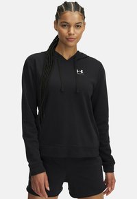 Sudadera con capucha negra hecha de tejido suave, con escote en V, mangas largas y un logo en la parte delantera. Combinada con pantalones cortos negros.