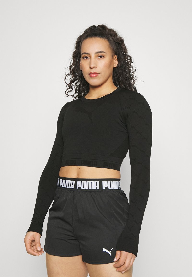 Must mustriga mustardiga crop-top, millel on tekstuuriga muster ja PUMA logo, koos mustade lühikestega, millel on elastne vöökoht ja logo aktsent.