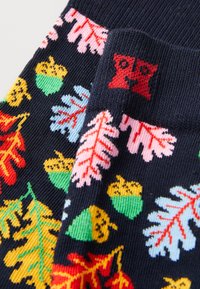 Chaussettes navy avec des feuilles d'automne colorées, des glands verts et un petit motif de visage d'ours rouge.
