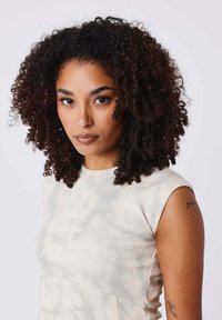 Haut sans manches beige clair avec un motif tie-dye, encolure ronde, et un design plissé, avec un branding subtil à l'avant.