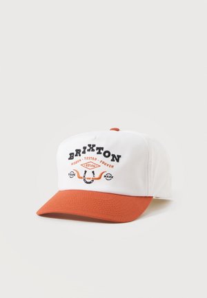 Hvitt og oransje baseballcaps med teksten "BRIXTON" og en broderi av en hestesko på frontpanelet mot en lys bakgrunn.