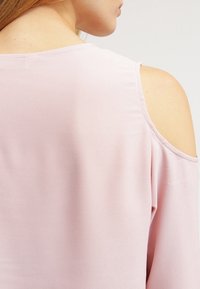 Top rosa, con una consistenza morbida, design con spalle scoperte e un ampio scollo. Tessuto fluido, leggero, adatto per un abbigliamento casual.