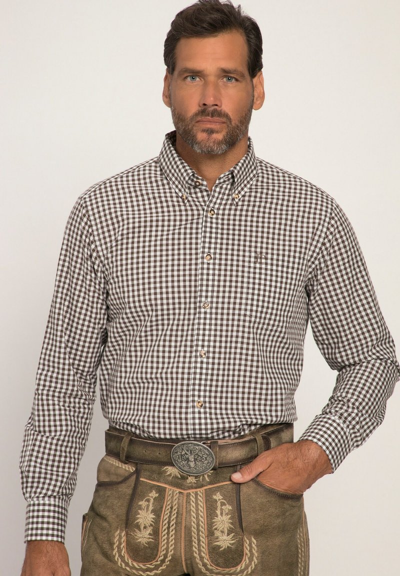 Braun-weiße karierte Langarmbluse mit Button-Down-Kragen, kombiniert mit dekorativen Ledershorts und einer Metall-Gürtelschnalle.