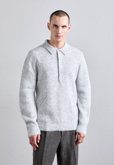 Light gray knitted sweater with a button-up collar, long sleeves, and ribbed cuffs and hem. Worn with gray trousers. Soft, textured material.