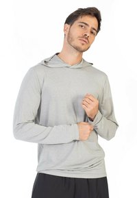 Hoodie grigio a maniche lunghe con tessuto testurizzato, dotato di cappuccio regolabile e vestibilità comoda, abbinato a pantaloni neri.