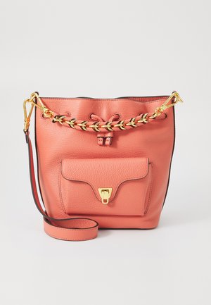 Peach leather bucket bag with gold chain accents, drawstring closure, and front pocket. Features a detachable shoulder strap.